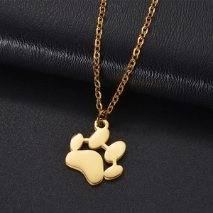 Detailed view of a gold paw print pendant necklace on a premium black leather texture