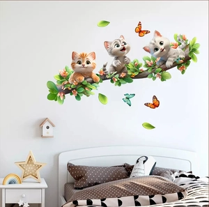 Detail of cartoon kittens on a branch wall sticker in a cozy nursery room setting