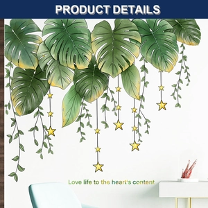 Detail von tropischen Monstera-Wandstickern mit goldenen Sternen auf weißer Wand