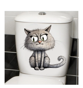 Close-up of a funny cartoon cat toilet sticker with green eyes on white bathroom cistern