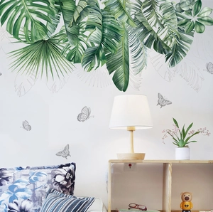 Detail of tropical palm and monstera leaf wall stickers with watercolor butterflies in a bedroom