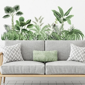 Tropical green leaf wall stickers featuring palm and banana leaves over a gray sofa