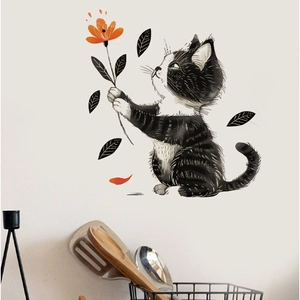 Cartoon black cat wall sticker holding an orange flower on a white living room wall