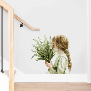 Détail d'un sticker mural montrant une fille avec du muguet sur un mur d'escalier