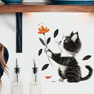 Detail of cartoon black cat wall sticker holding an orange flower on white wall