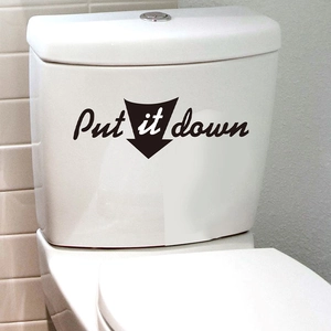 Détail du sticker noir 'Put it down' en vinyle sur l'abattant de toilette blanc