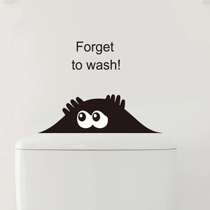 Close-up of funny black monster wall sticker with Forget to wash text on white toilet tank