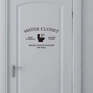 Macro detail of black PVC vintage water closet wall decal on a white bathroom door