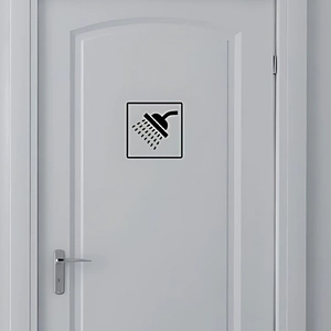 Detail view of square black and white shower icon sticker on a white wooden bathroom door