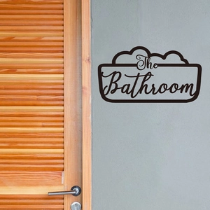 Modern black 'The Bathroom' wall decal with bubble border on gray wall next to wood door