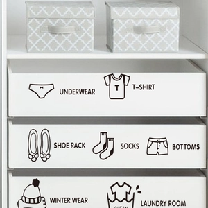 Detail of black vinyl clothing organization stickers applied to white closet drawers
