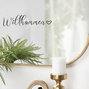 Detail of black Willkommen lettering sticker with heart icon on a bathroom mirror