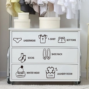 Close-up of black self-adhesive clothing category icons on white storage drawers