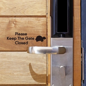 Close-up of Please Keep The Gate Closed door sticker with turtle icon and door handle