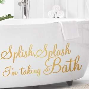 Golden vinyl bathroom wall decal with 'Splish Splash' quote applied to a white bathtub