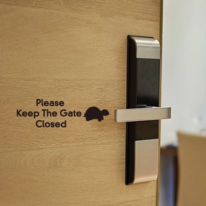 Close-up of Please Keep The Gate Closed turtle vinyl sticker on a modern wooden door