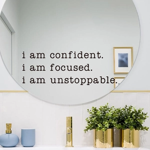 Close-up of motivational vinyl wall stickers with black lettering on a bathroom mirror