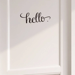 Vue macro du sticker mural hello. noir minimaliste sur une porte intérieure blanche