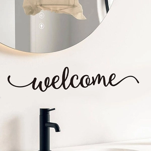 Detail of artistic black cursive welcome wall decal on a modern minimalist white wall