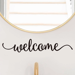 Minimalist black welcome cursive wall decal sticker under a round gold mirror decor
