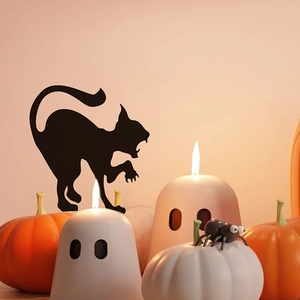 Close-up of black cat silhouette wall sticker with Halloween pumpkins and candles