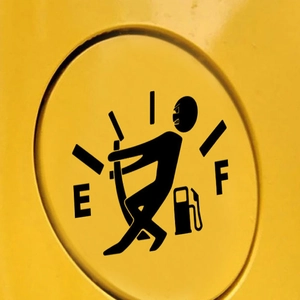 Close-up of a funny cartoon figure pulling the fuel gauge needle on a yellow car gas tank