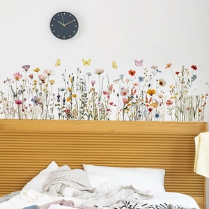 Detail of hand-painted floral wall stickers with colorful flowers and butterflies above a bed