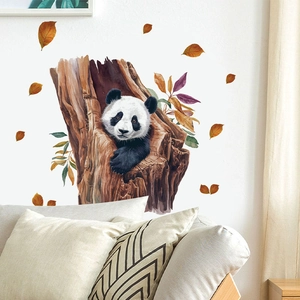 Detail of a watercolor panda wall sticker in a tree hole with autumn leaves on a white wall