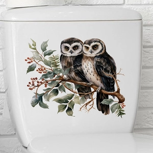Detail of owl and berry decal sticker applied on a white ceramic toilet tank surface