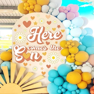 Bohemian arch backdrop with Here Comes The Sun text and daisy patterns for party decor