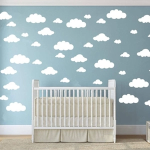 Detailed view of white cloud wall decals applied on a blue nursery wall above a baby crib