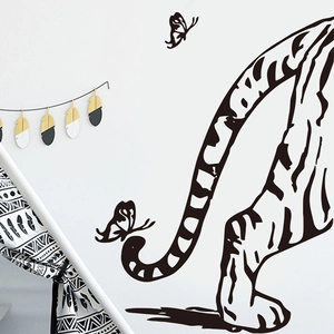 Detailed view of black tiger tail wall decal with butterflies in cozy bedroom setting