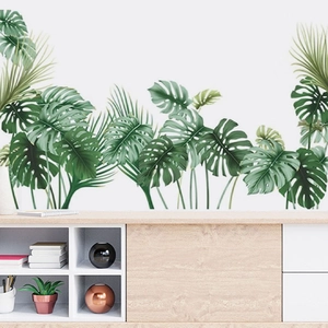 Detail of tropical Monstera and palm leaf wall stickers on a clean white living room wall