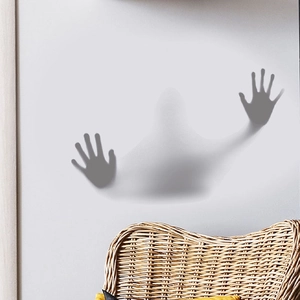 Spooky 3D ghost shadow handprints wall sticker on a white wall above a rattan chair