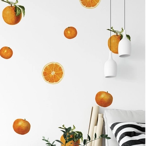 Detail of vibrant orange fruit wall stickers on a clean white wall in a modern living room