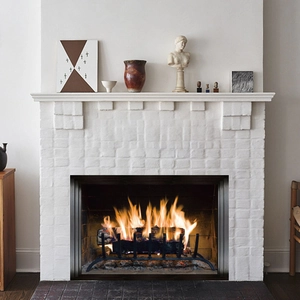 Classic fireplace insert with glowing logs and metal grate in an elegant white mantel