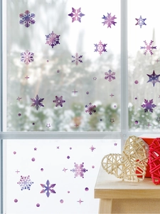 Détail de stickers flocons de neige violets et étoiles sur vitre avec décor de fête hiver