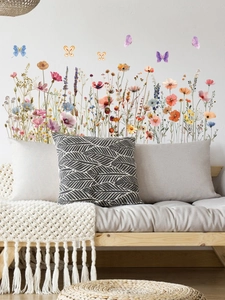 Détail de stickers muraux fleurs sauvages et papillons sur un mur blanc au-dessus d'un canapé