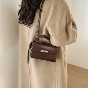 Detail of adjustable dark brown lychee pattern PU leather strap on a small crossbody bag