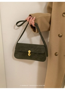 Détail d'un sac à bandoulière en daim vert foncé avec boucle métallique dorée en forme de U