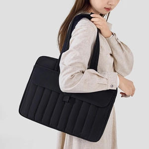 Dettaglio di una borsa tote nera trapuntata per laptop con cuciture verticali