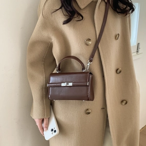 Detail of vintage brown PU leather crossbody bag with polished metallic clasp and top handle