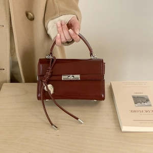 Close-up of wine red patent leather handbag with silver heart charm and metal feet