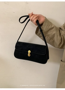 Détail d'un sac minimaliste en daim noir avec un fermoir rotatif en métal doré chic