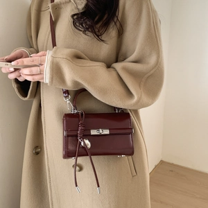 Detail of wine red glossy leather shoulder bag with silver heart pendant and metal clasp