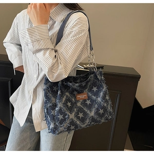 Close-up of distressed denim tote bag featuring frayed star patterns and chain strap