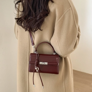 Detail view of burgundy leather handbag with adjustable shoulder strap and metal hardware