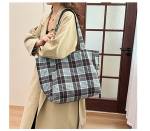 Détail d'un grand sac cabas en laine à carreaux bleus porté avec un trench-coat kaki