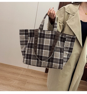 Détail du grand sac cabas en laine à carreaux style anglais porté sur un trench-coat