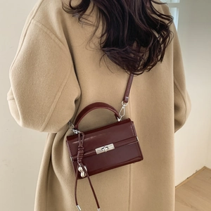 Detail of burgundy PU leather shoulder bag with silver heart charm and metal lock